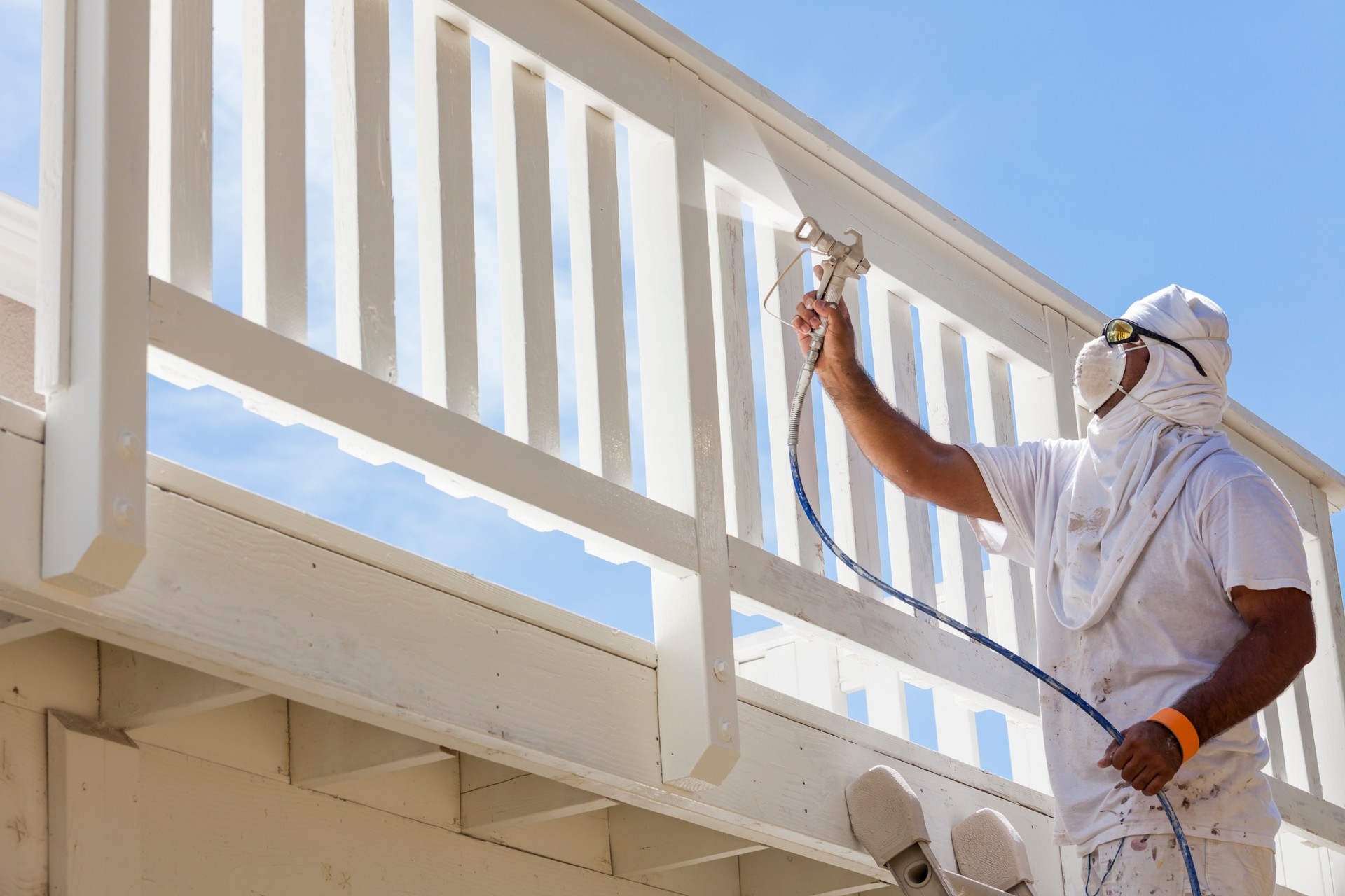 House Painter Spray Painting A Deck of A Home